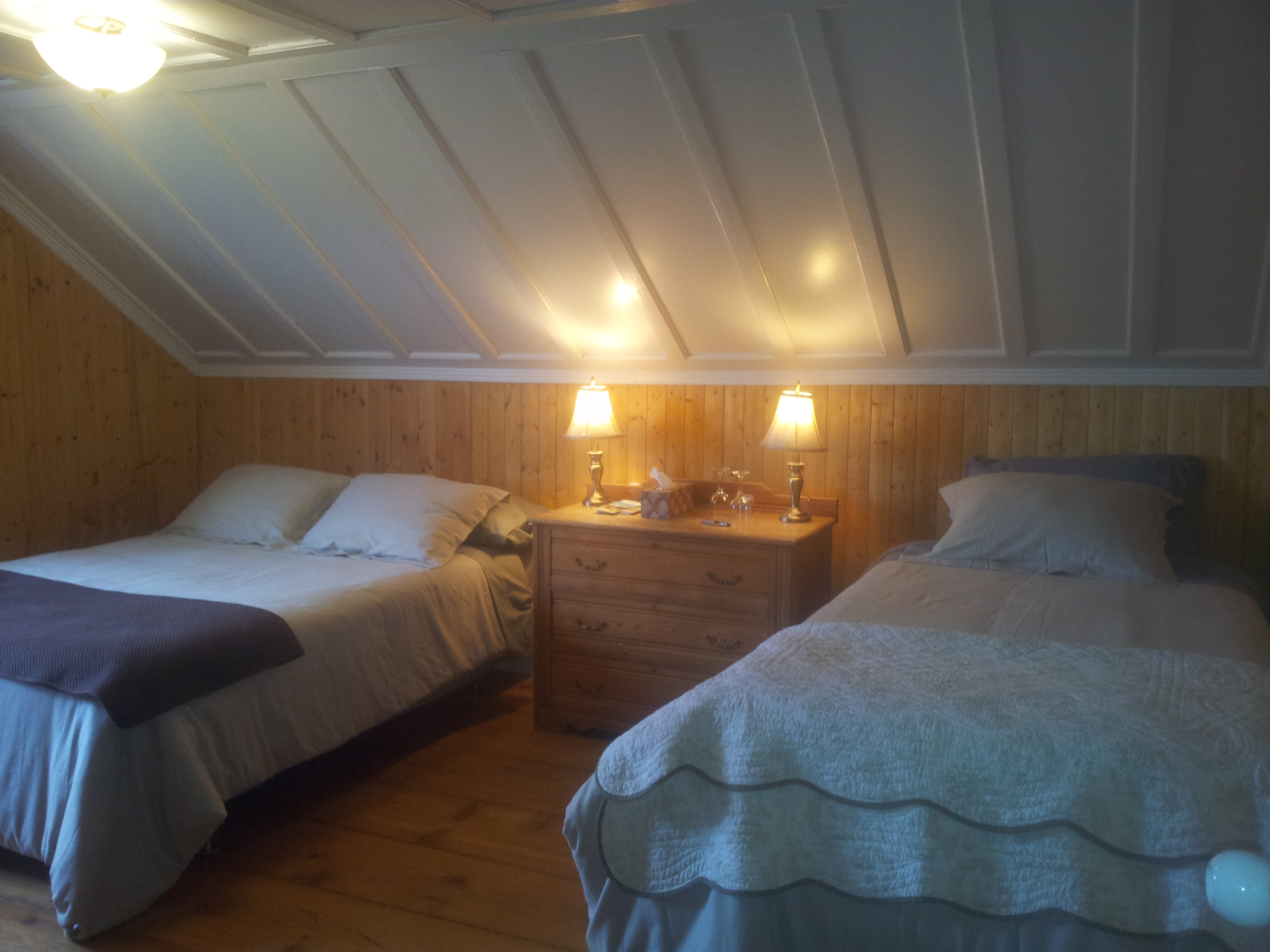 Charmante chambre côté jardin doté d'un lit double extra long et d'un lit simple. Chaleureuse finition en bois.